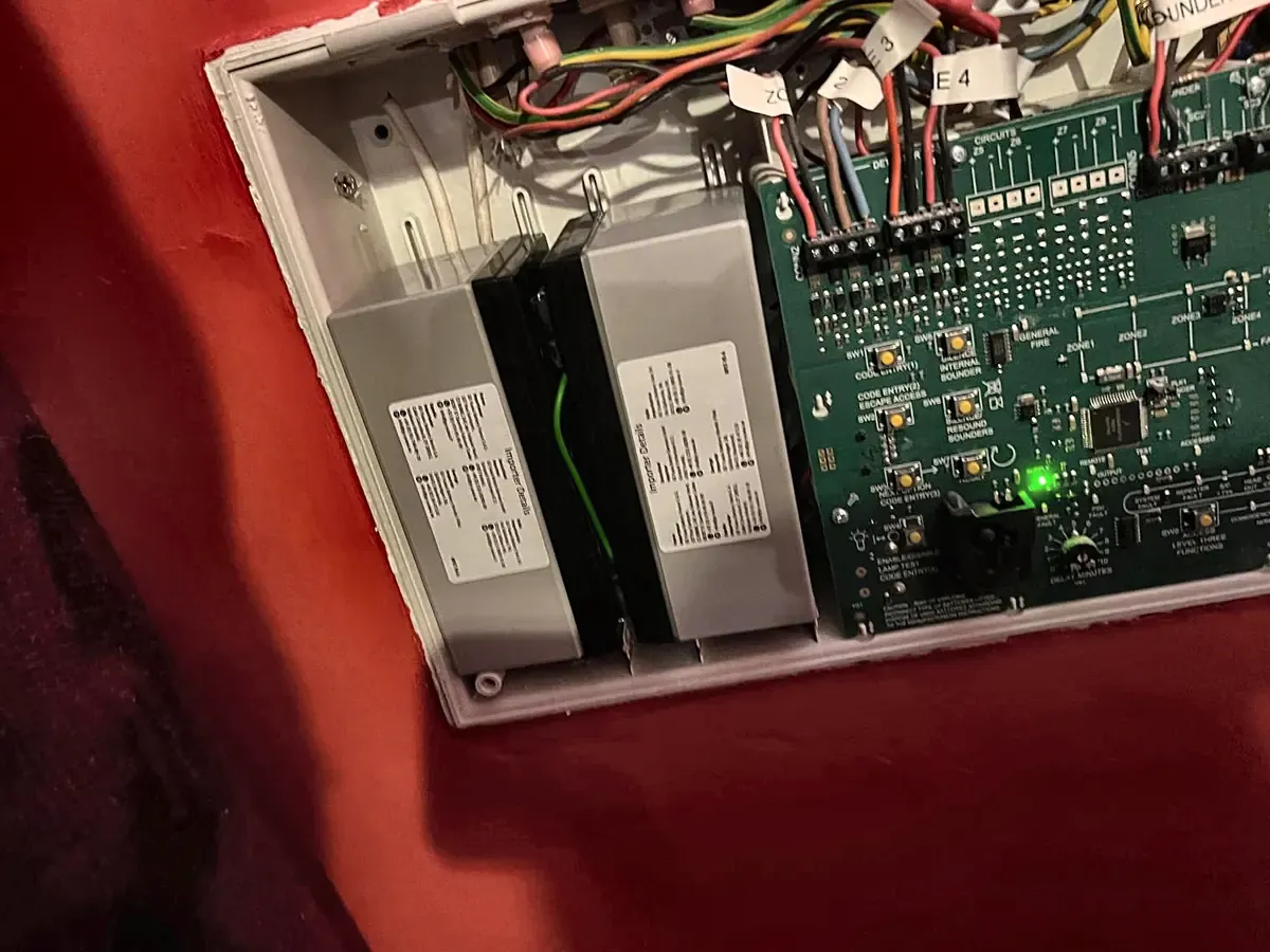 Inside a fire alarm panel opened on a service visit: the standby batteries on the left, the main board on the right